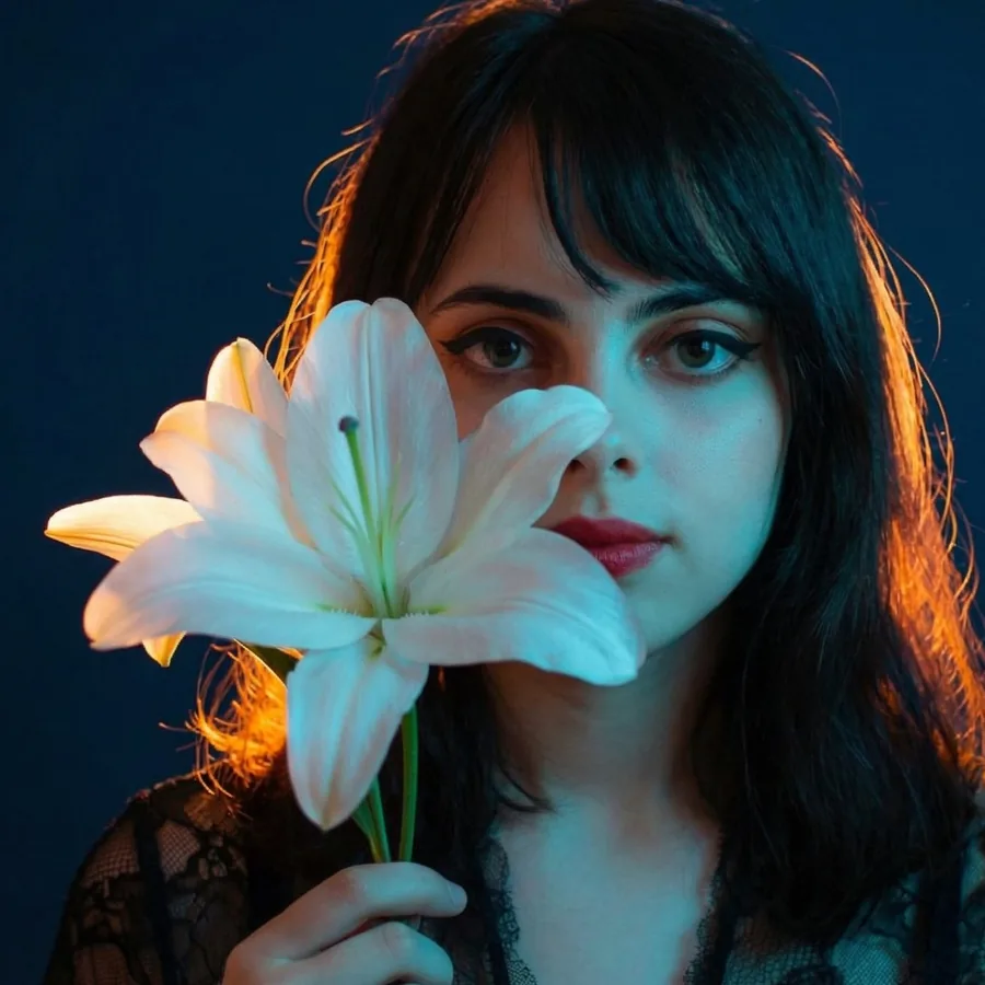 Lily holding a white lily in front of her face