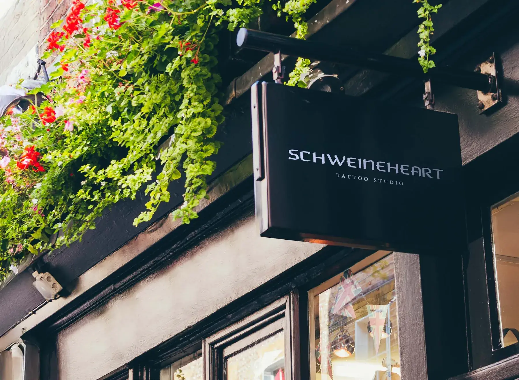 The Schweineheart hanging shop sign under flower boxes