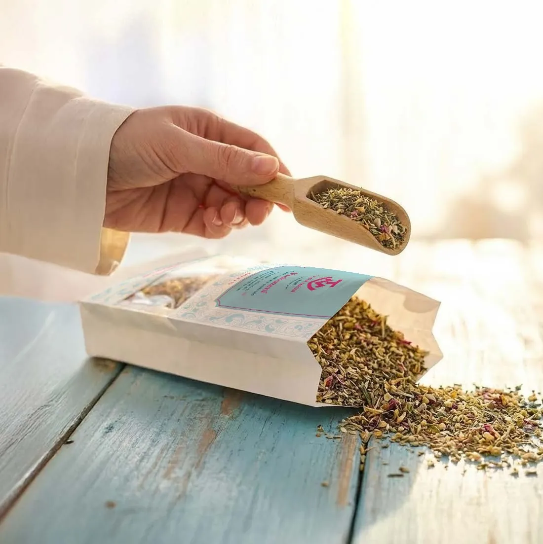 A wooden scoop of loose-leaf herbal tea poured from a Terra Mater pouch